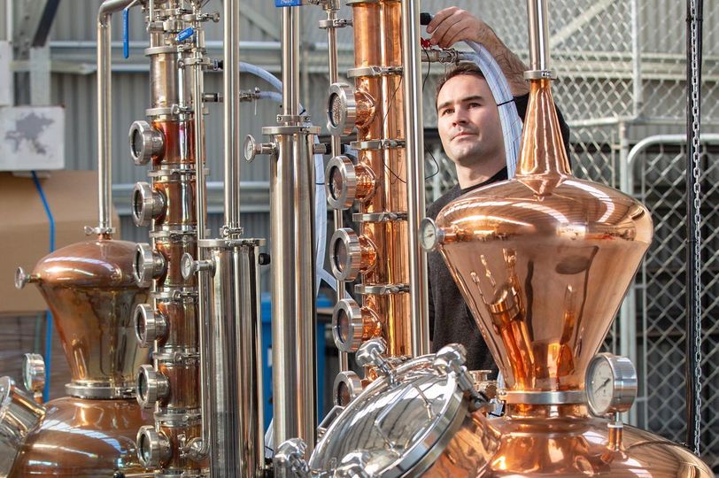 Man adjusting gin making equipment 