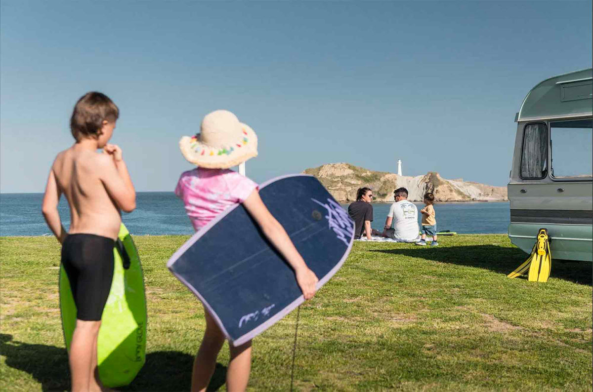 kids holding boogie boards at the coast