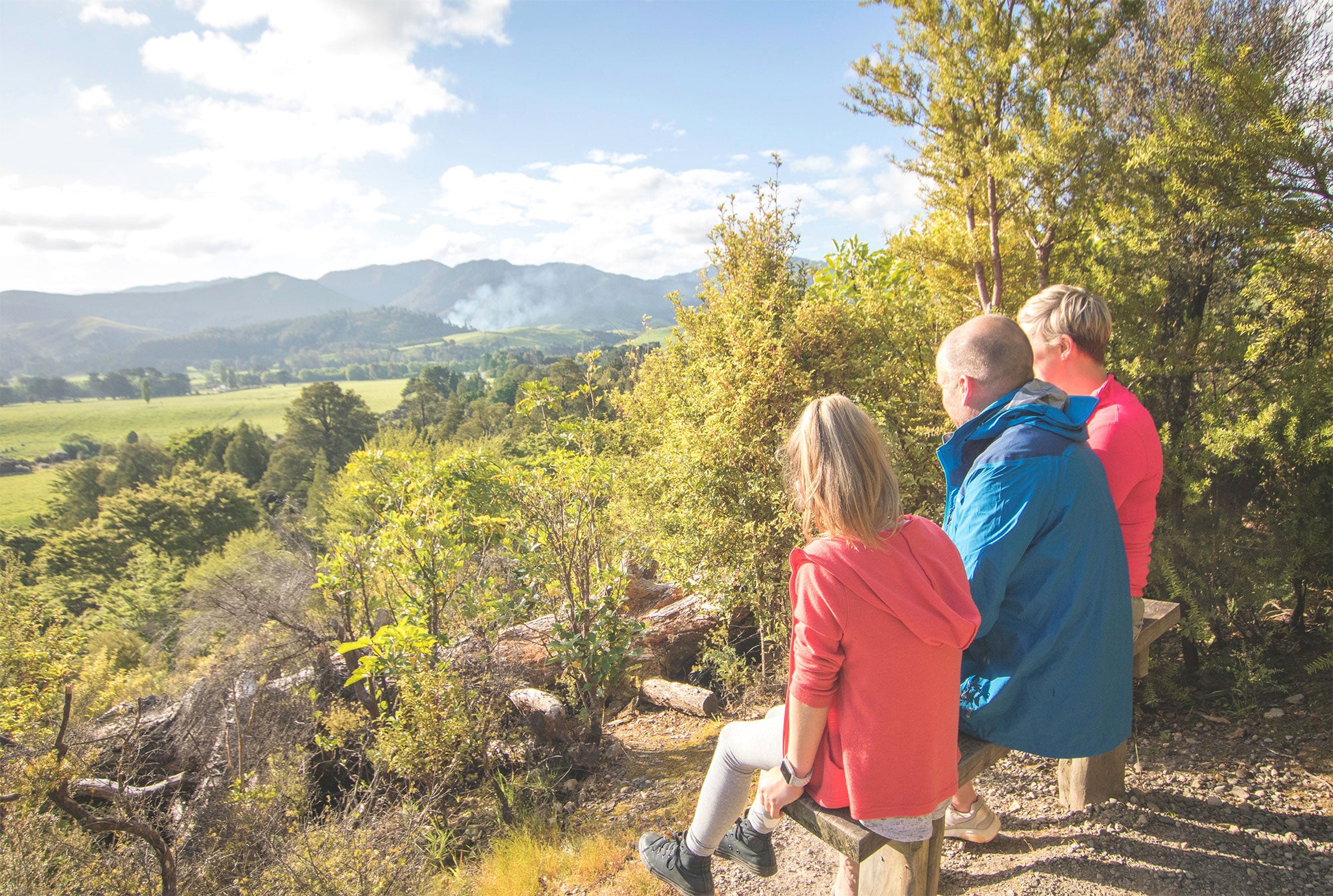 Family sitting on bench looking at view 