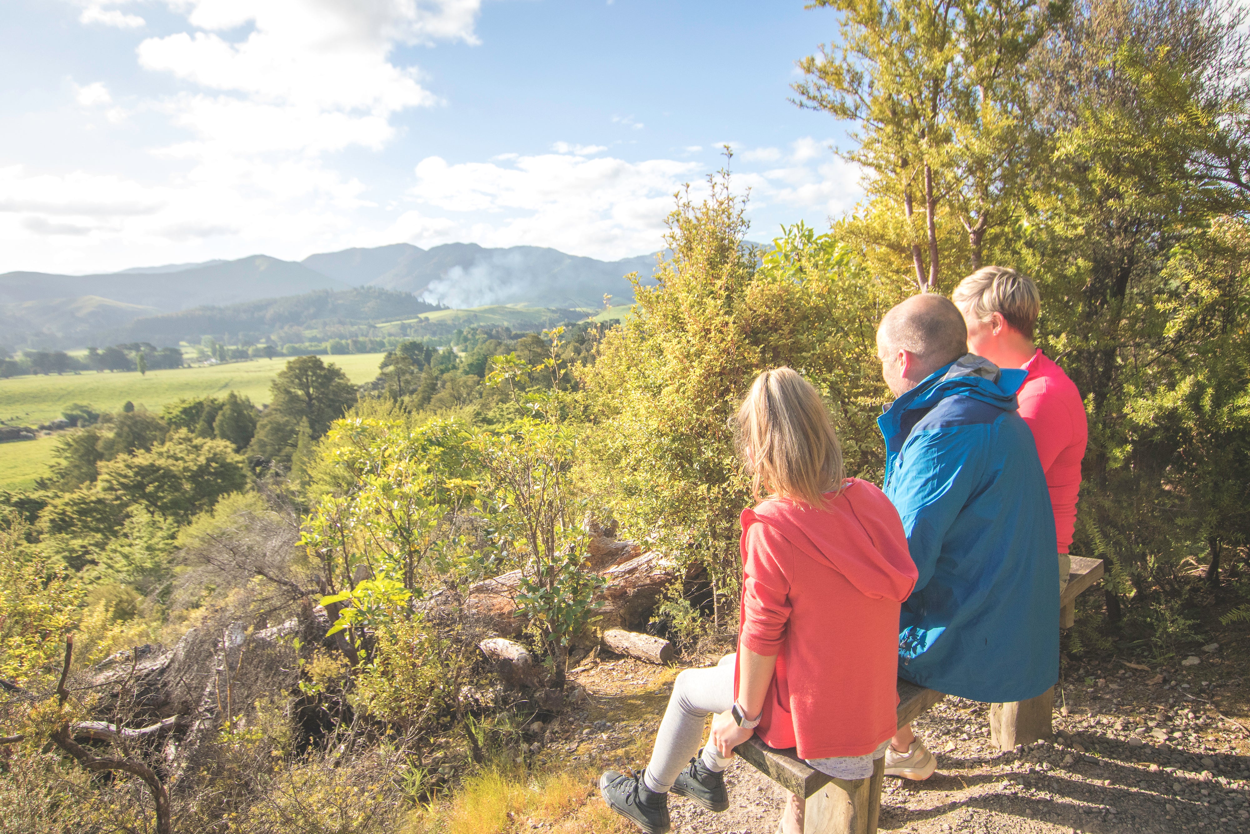 Family sitting on bench looking at view 