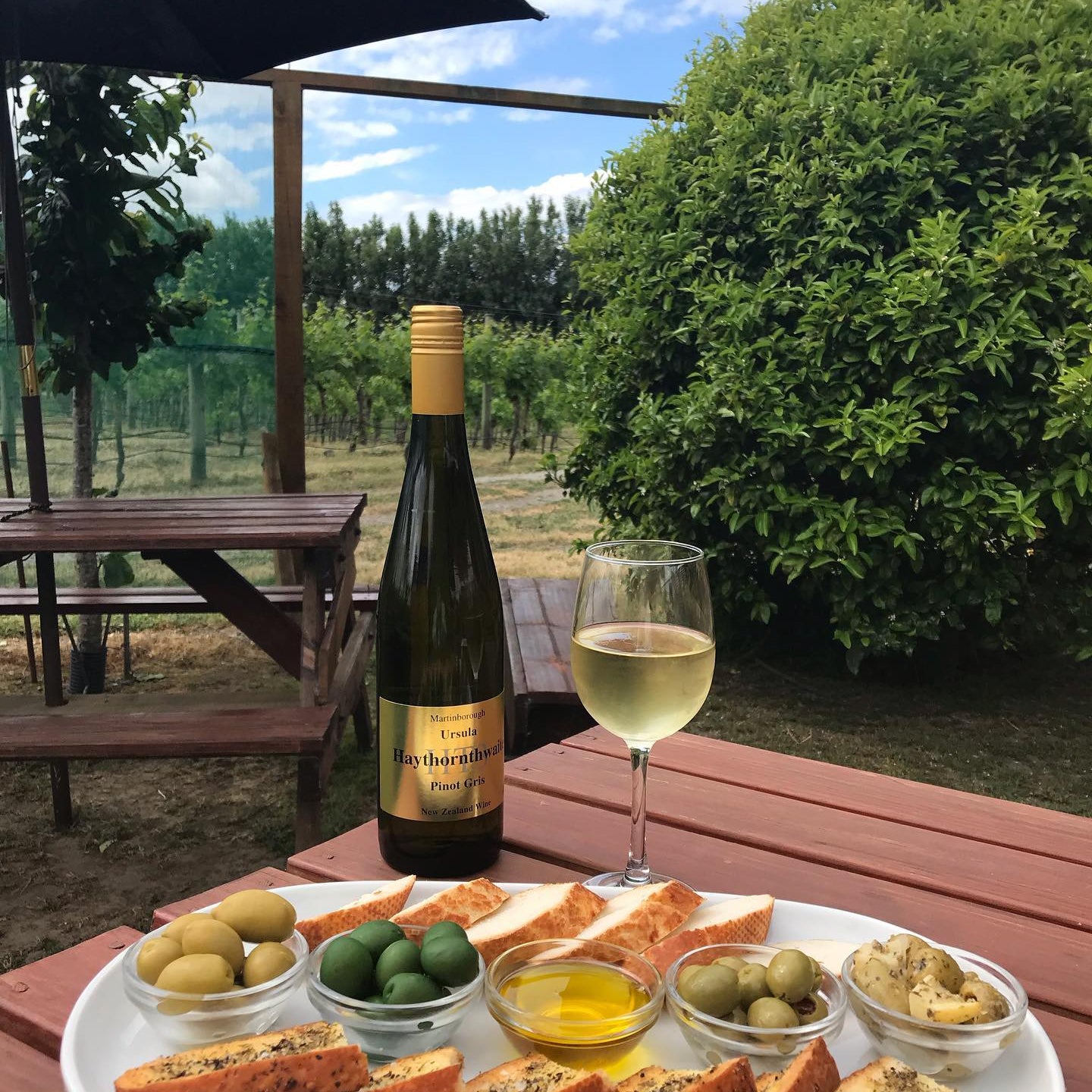 Wine bottle, glass and platter of food on table 