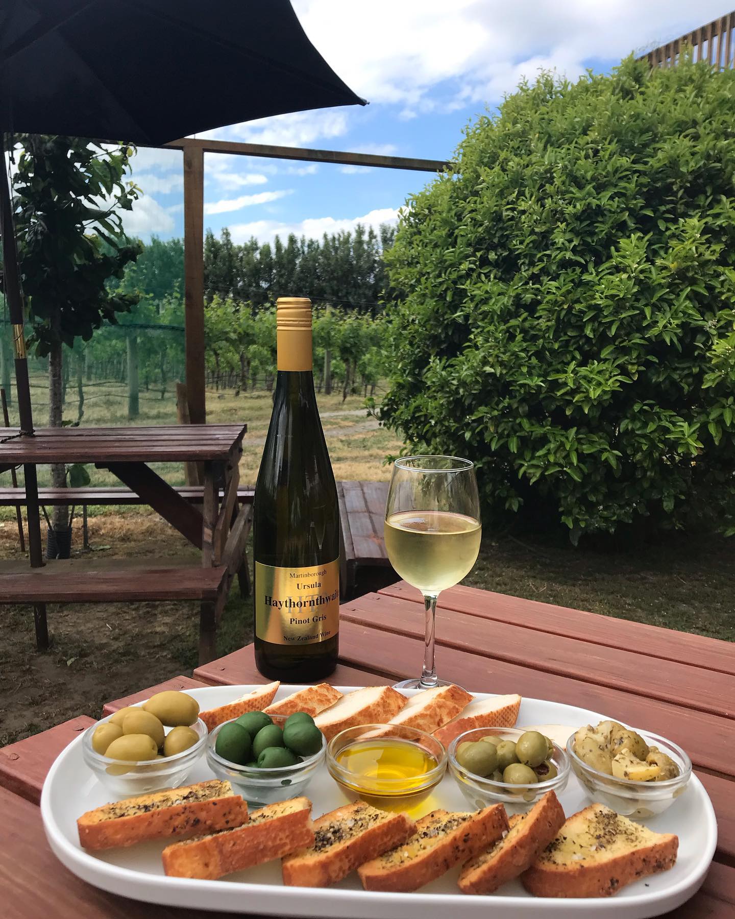 Wine bottle, glass and platter of food on table 