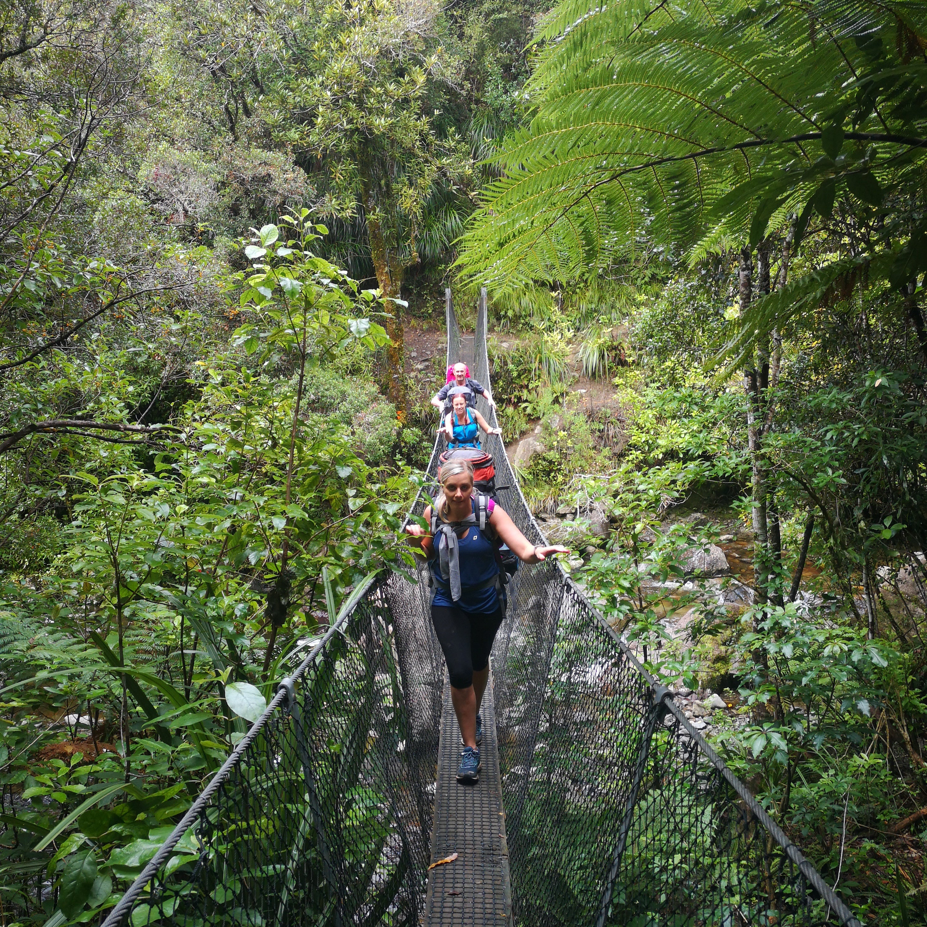 Trampers walking across swing bridge 