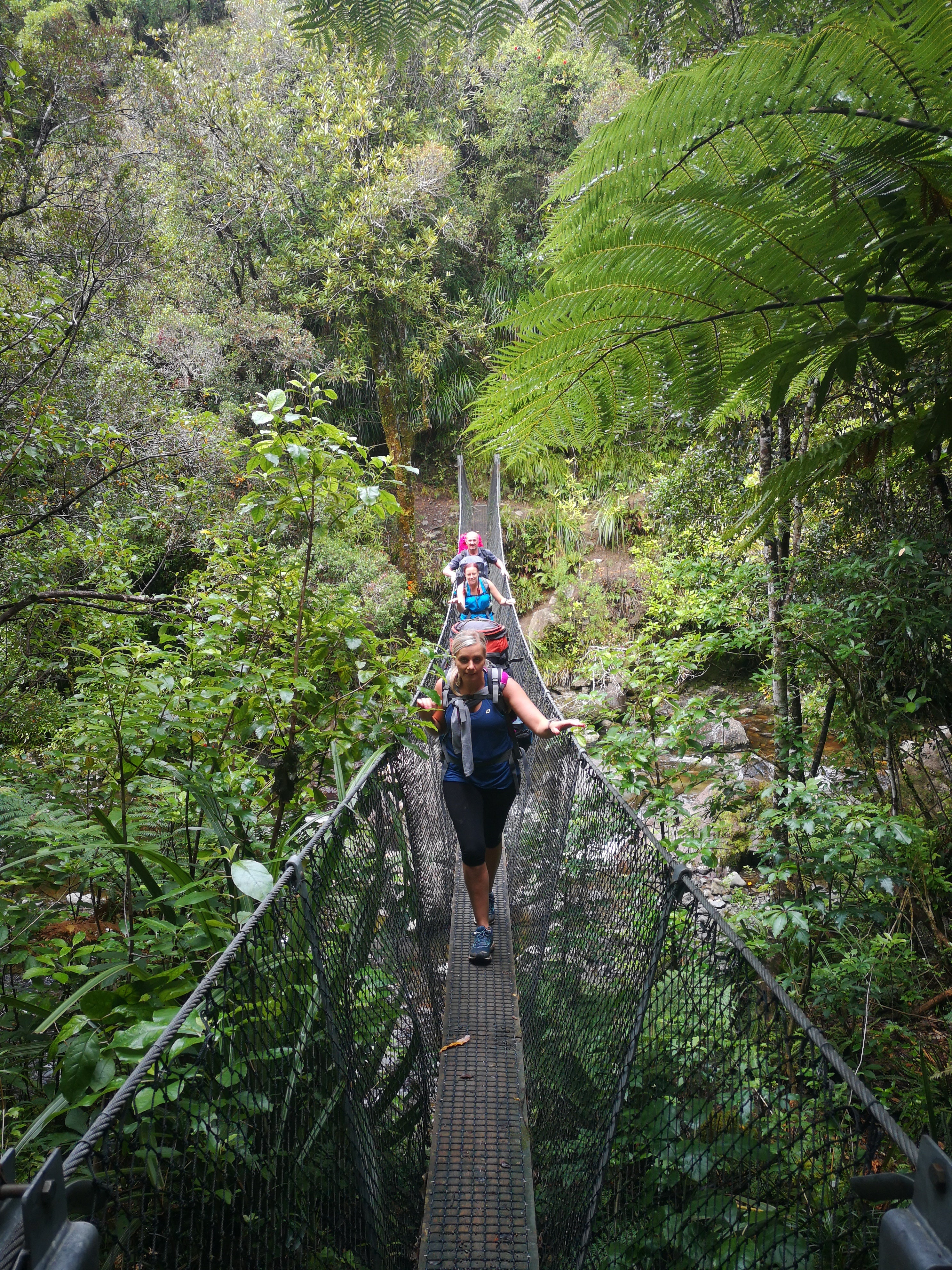 Trampers walking across swing bridge 