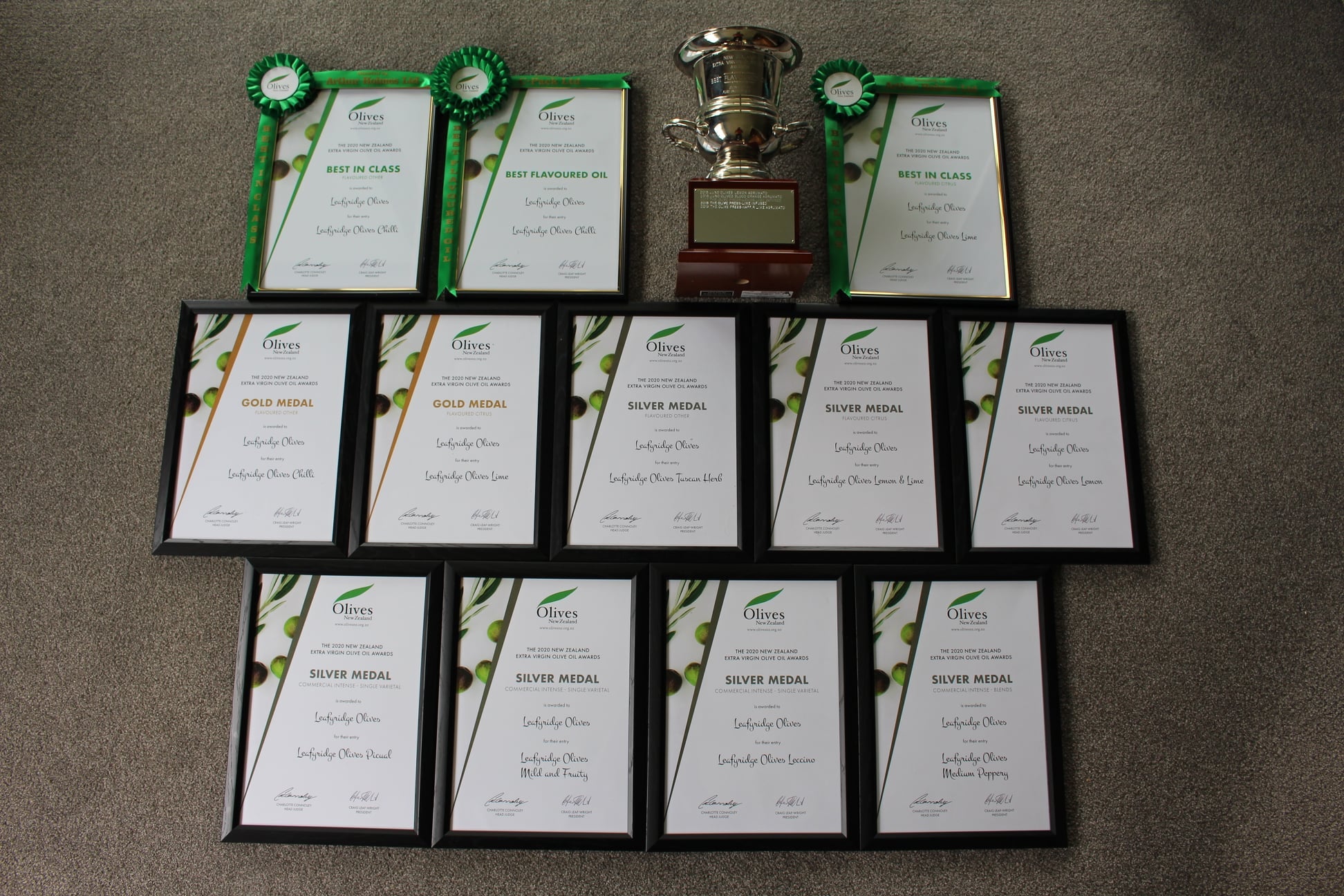 Many framed awards and a trophy for olive oil quality 