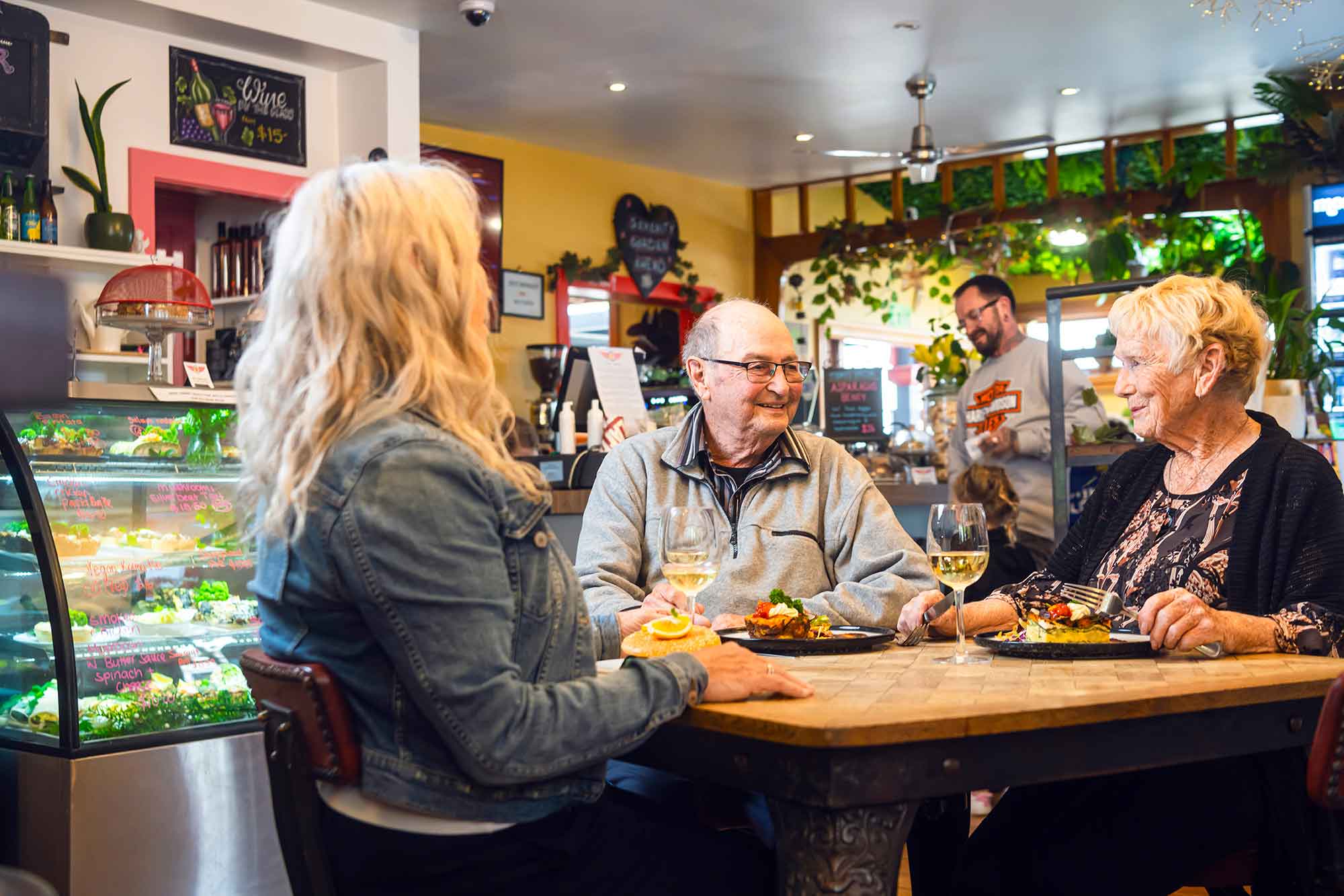 People sitting at a table in a cafe with drinks and food