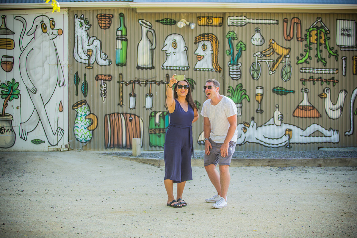 Couple taking a selfie in front of mural 