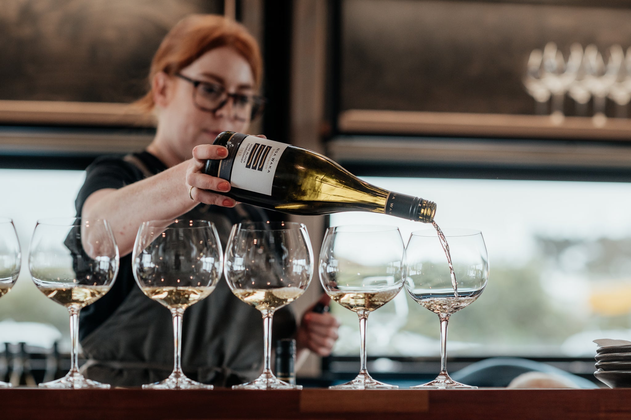 Lady pouring glasses of wine at bar 