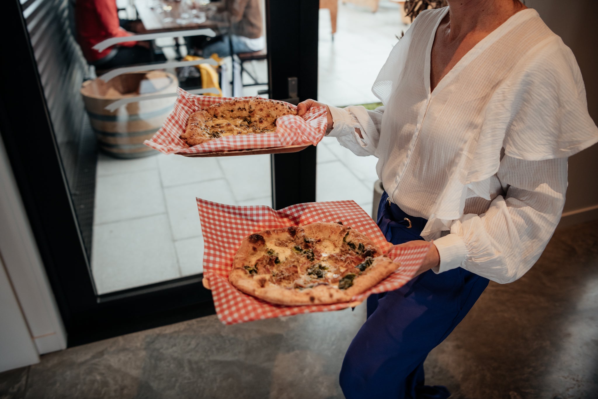 Lady carrying two freshly made pizzas 