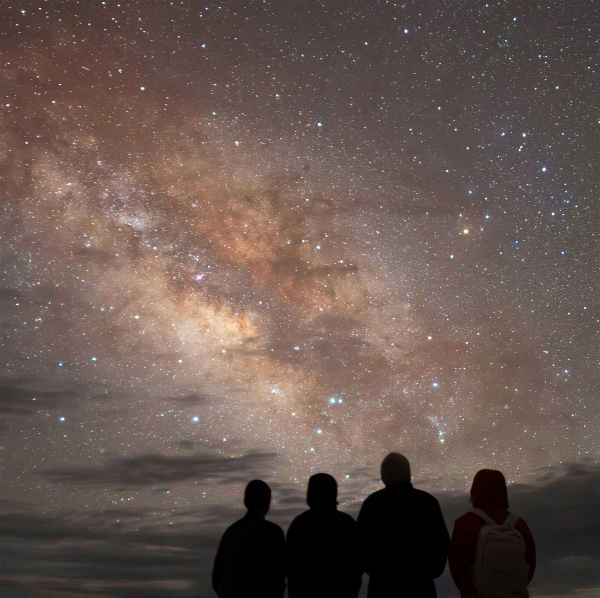 Four people gazing up at the Milky Way galaxy