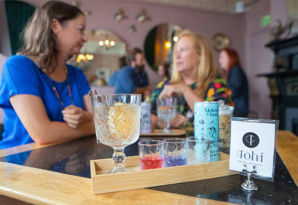 A tray containing glasses of gin with people in the background