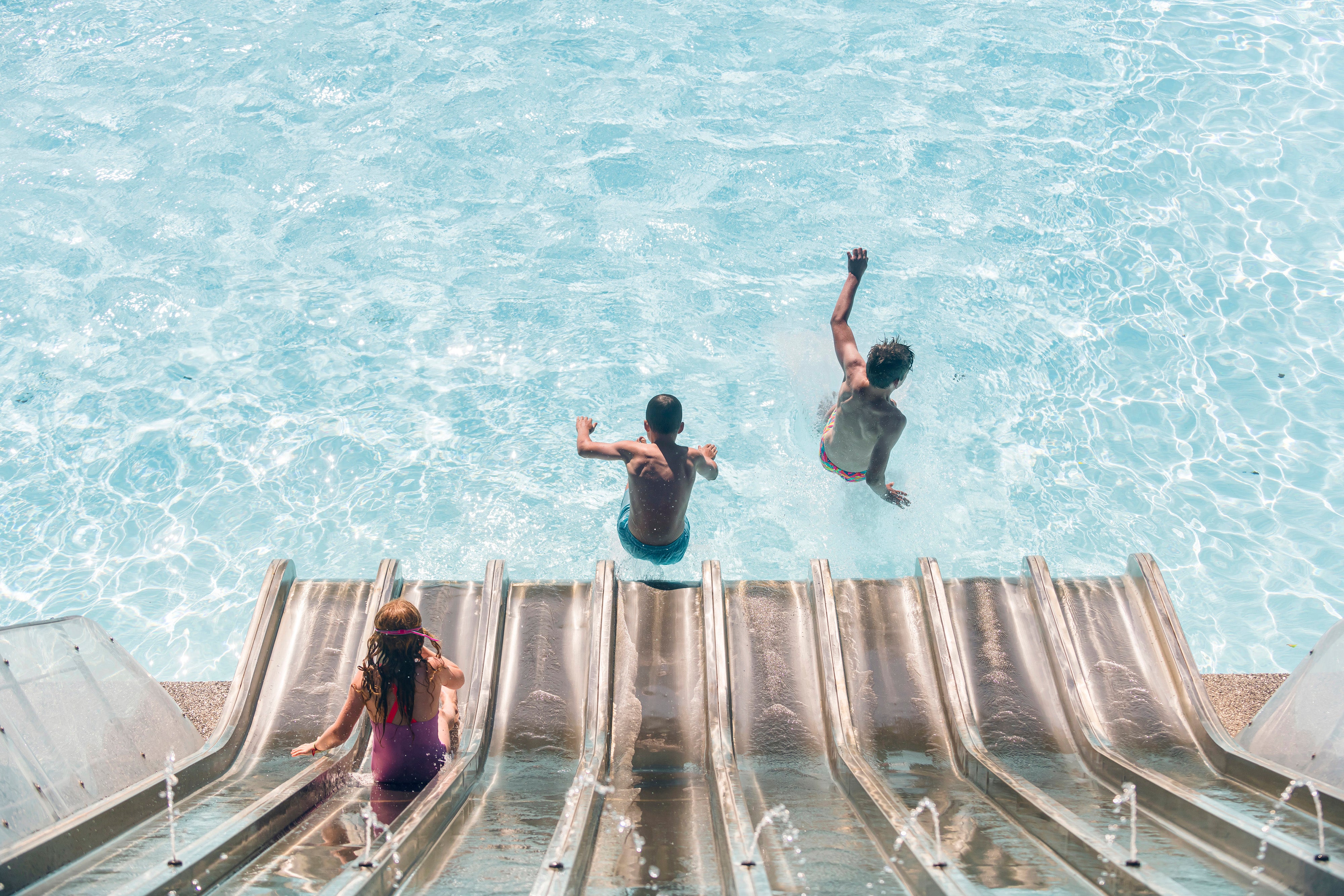 Aerial view of kids sliding into pool 