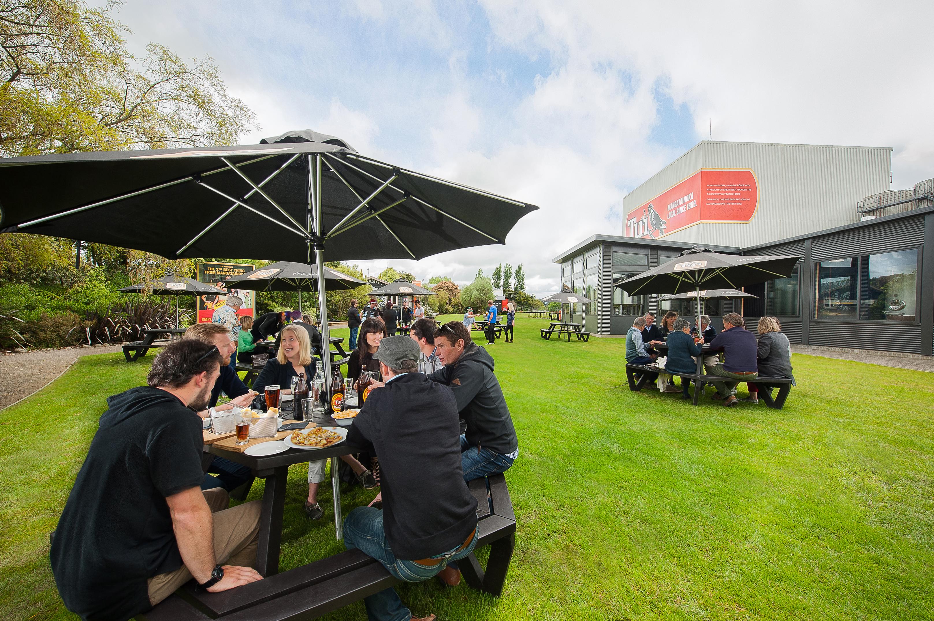 People enjoying food and beer at tables on the lawn 